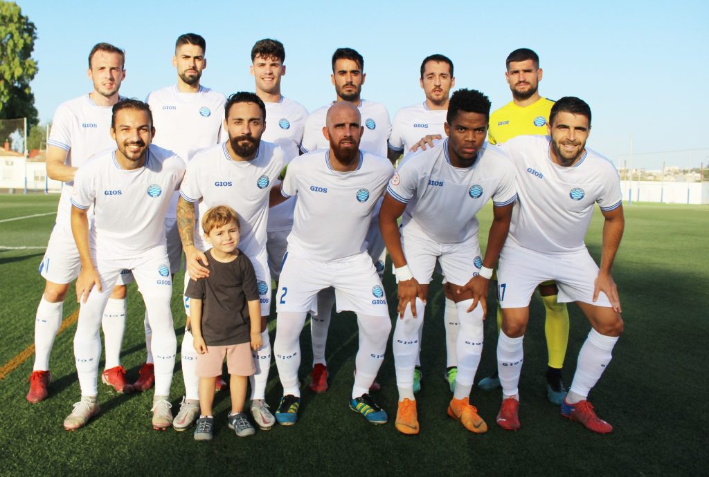 Once del Unión Molinense con equipación blanca posando junto a un niño